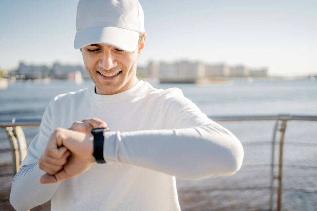 Fitness electronic watch on hand running male athlete conducts fitness training in the city, Healthy lifestyle