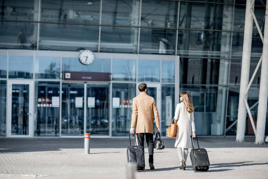 Business couple walking with luggage to the airport entrance